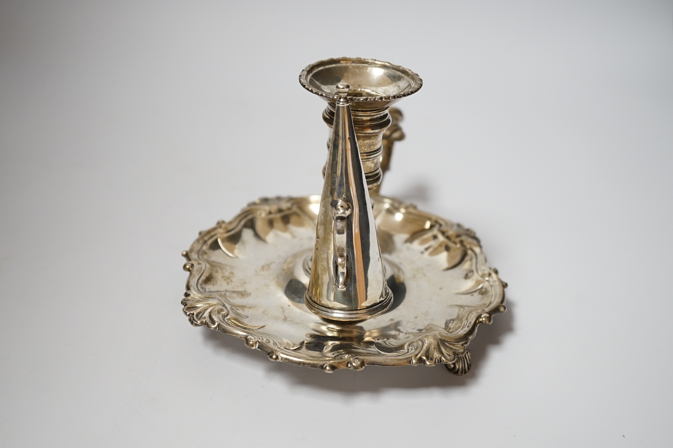 A George II silver chamberstick, with shell border, on three scroll feet, William Grundy, London, 1756, with extinguisher(marks rubbed), overall 18.5cm, 14.1oz.